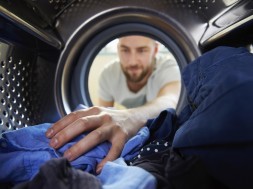 Man Doing Laundry Reaching Inside Washing Machine