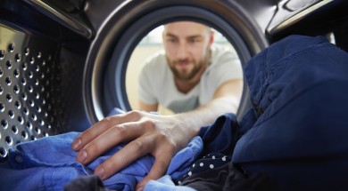 Man Doing Laundry Reaching Inside Washing Machine