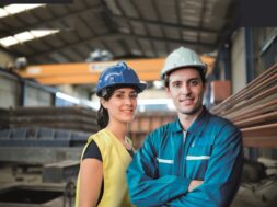 Pretty construction worker woman in factory looking smiling at camera