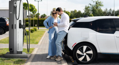 Couple Charging Electric Car at Charging Station on Sunny Day